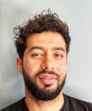 Portrait of Isshaq Albarbary in black and white in an oval shape.