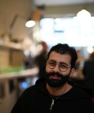 Portrait of Omar Abdellatif in black and white in an oval shape.
